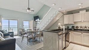 A spacious living area with a dining table, sofa, and a view of the ocean. - 38- Quaint, family friendly, 3 story condo on the gorgeous EMERALD COAST! (Destin)