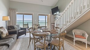 A spacious living area with a balcony overlooking the sea, furnished with a sofa, chairs, and a dining table. - 38- Quaint, family friendly, 3 story condo on the gorgeous EMERALD COAST! (Destin)