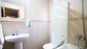 Un baño con lavamanos, inodoro y ducha.