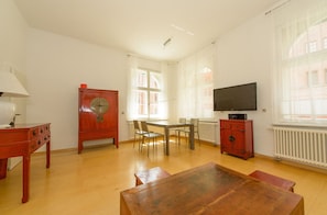 A spacious living room with a wooden table, chairs, a television, and a radiator. - Fewo auf der Dominsel Mühlendamm (Brandenburg an der Havel)