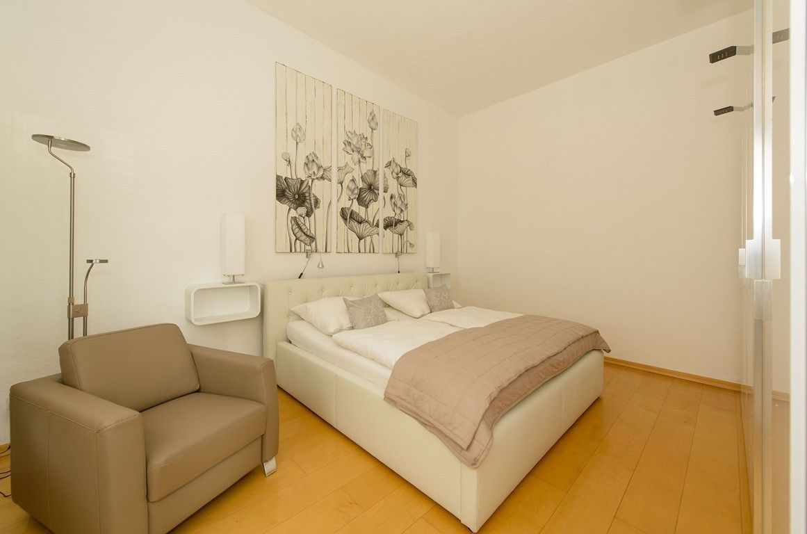 Un dormitorio con cama, sofá, lámpara de pie y una obra de arte en la pared.