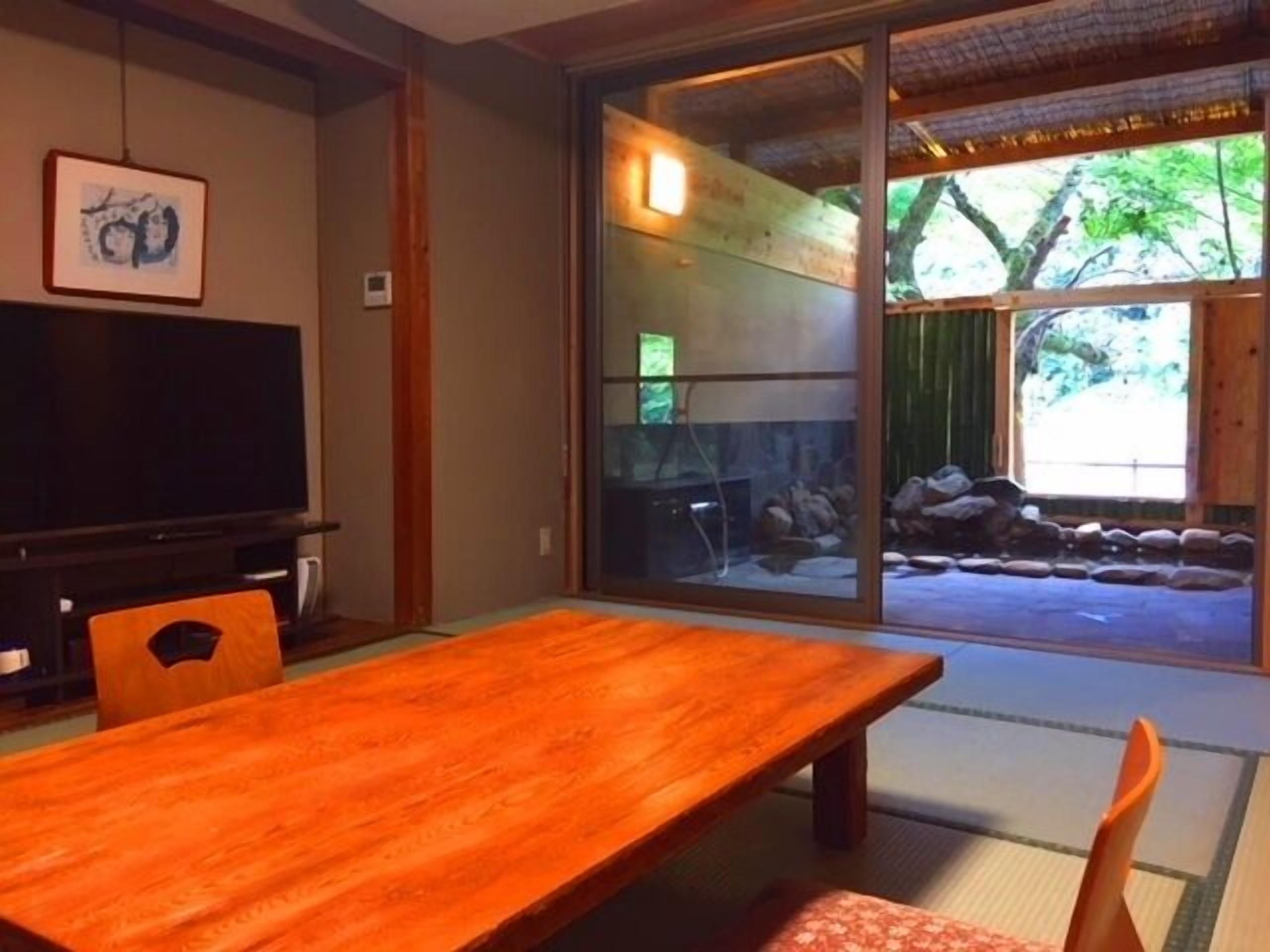 A traditional Japanese room with tatami flooring, a low table, and a television.