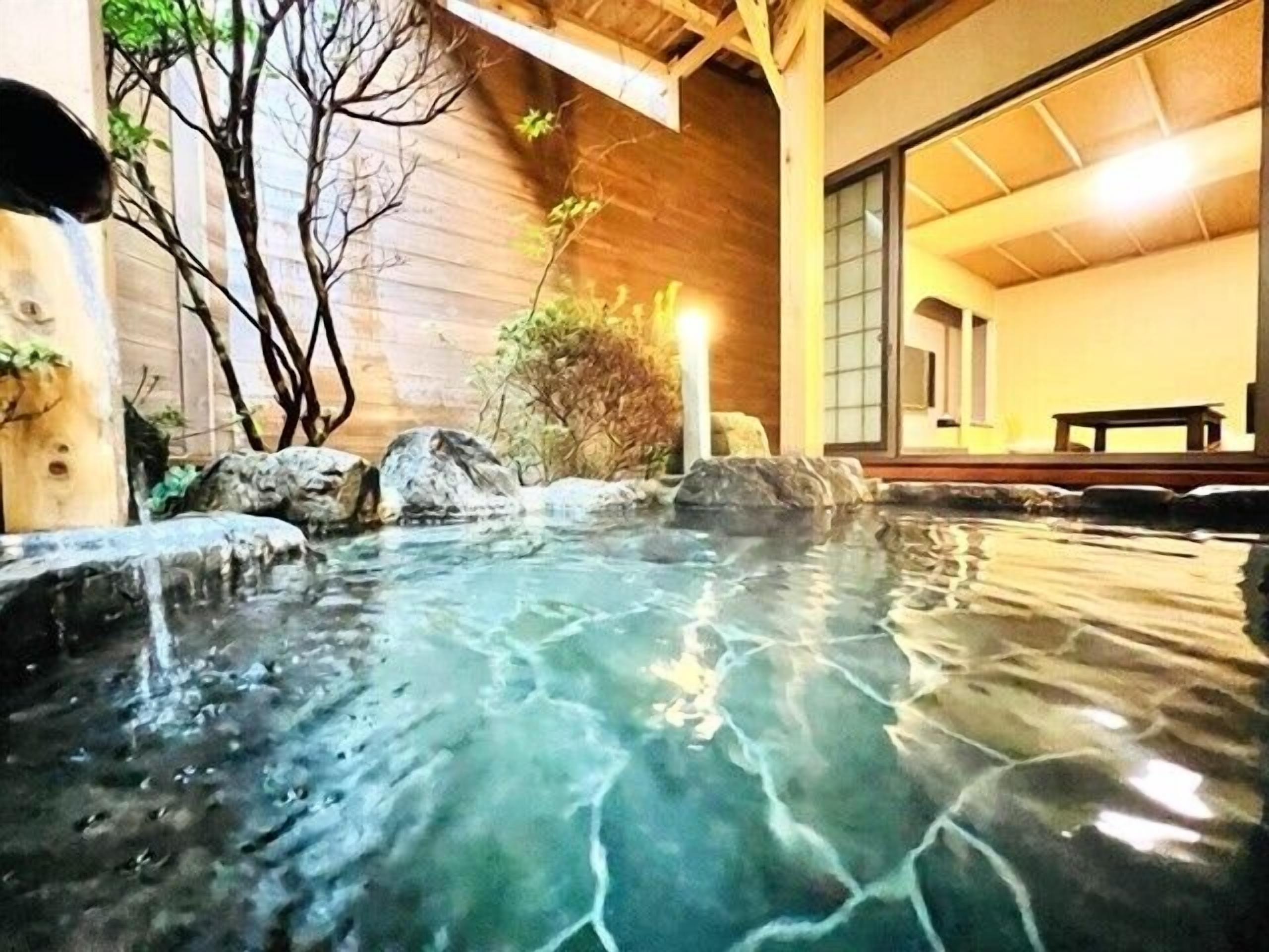 A hot spring area with clear water, rocks, and wooden structures.