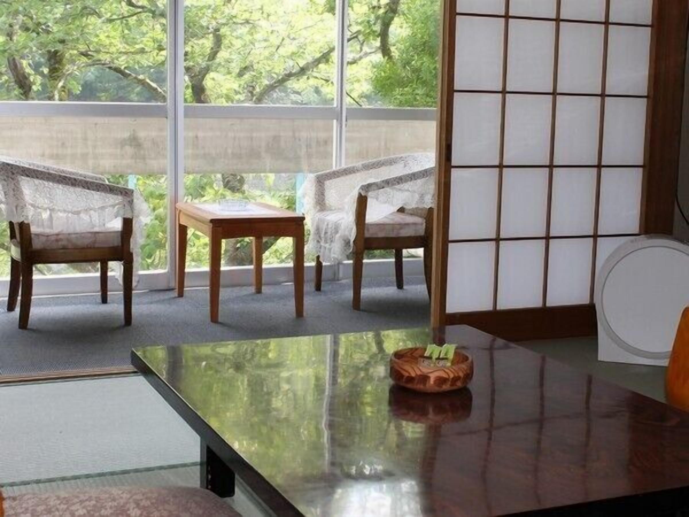 A traditional Japanese room with tatami flooring, a low wooden table, and two chairs.