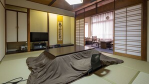 Een kamer met tatami matten, een lage tafel, een televisie en verschuivende shoji deuren.