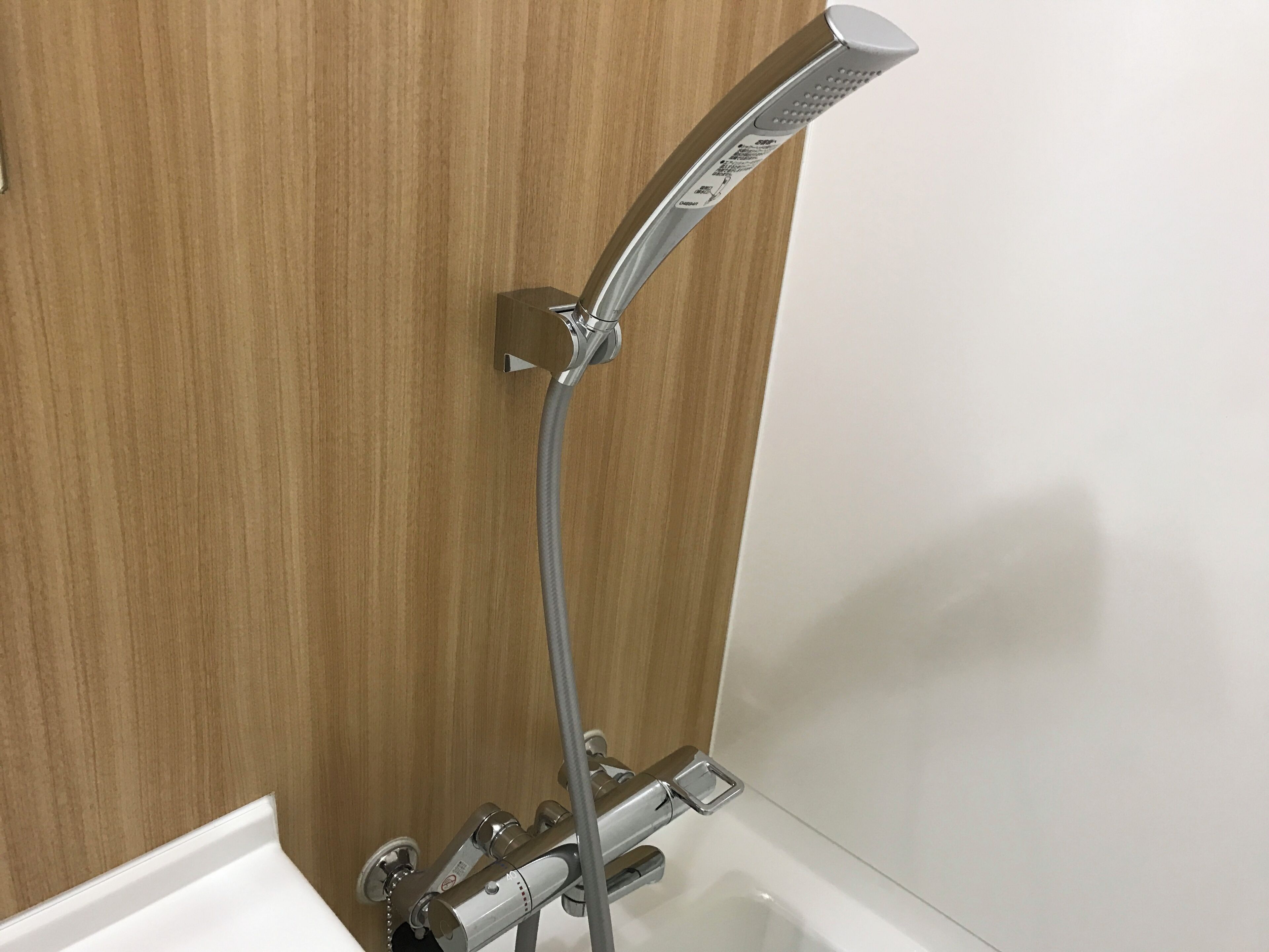 A modern shower with a handheld showerhead and a fixed wall-mounted faucet.