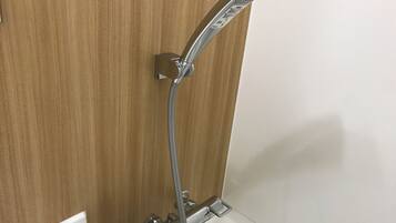 A modern shower with a handheld showerhead and a fixed wall-mounted faucet.