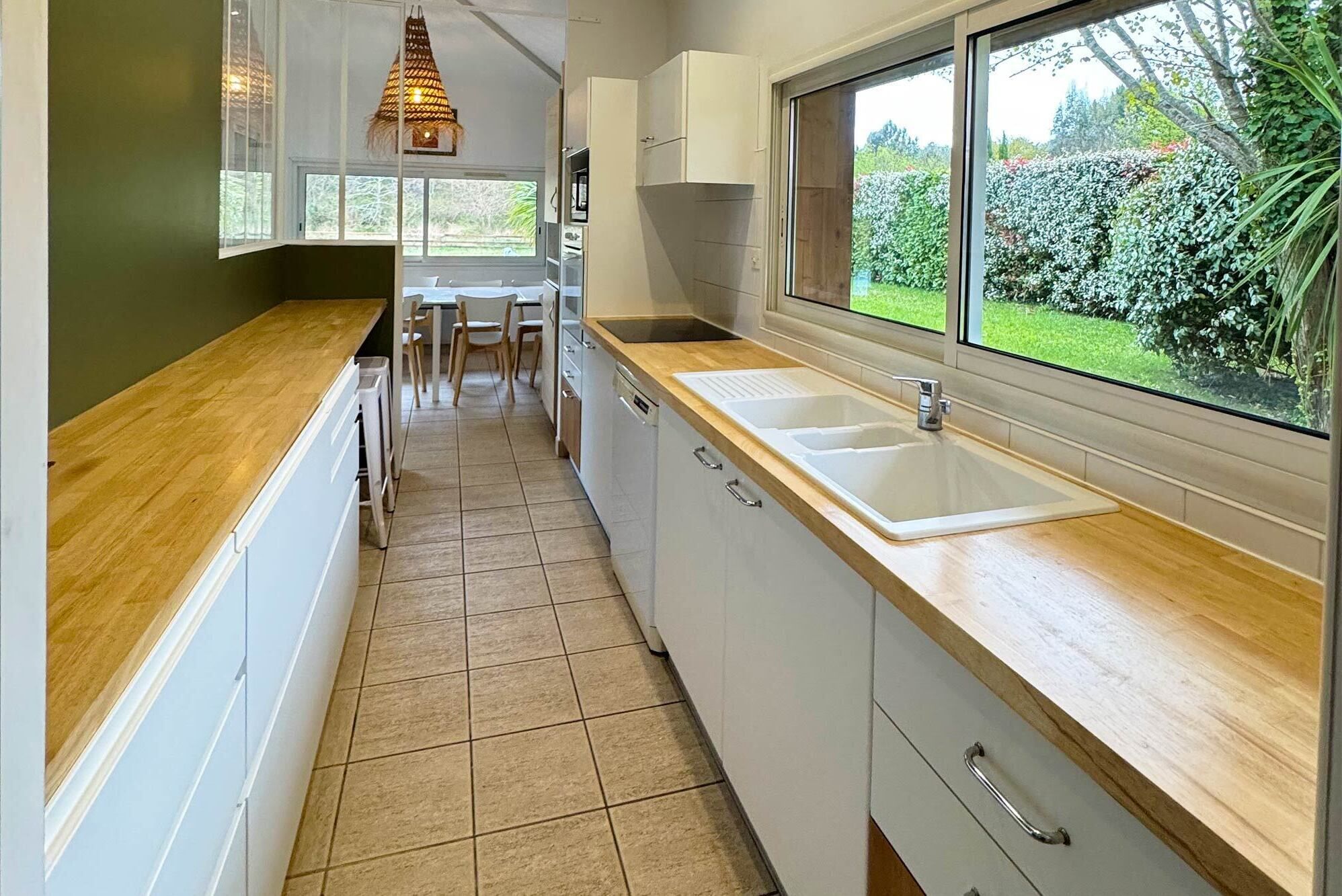 A kitchen with a wooden countertop, a sink, and a window overlooking a garden.