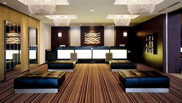 A modern hotel lobby with a reception desk, plush seating, and decorative chandeliers. - International Hotel Ube (Ube)