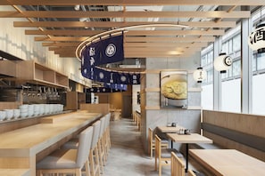 L’intérieur d’un restaurant, avec des meubles en bois, des drapeaux suspendus et une grande fenêtre.