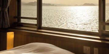 Una habitación con cama, ventana con cortinas y vista al mar.