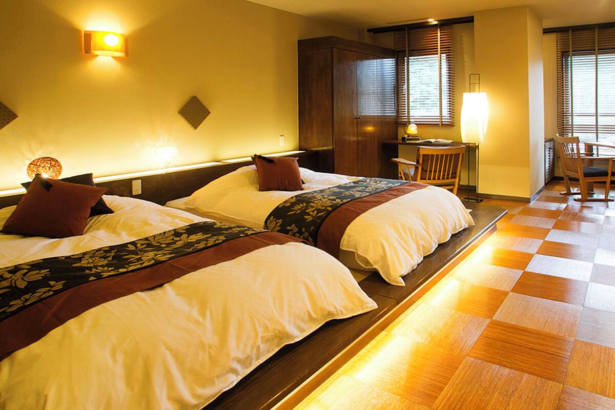 Ein Hotelzimmer mit zwei Betten, einem Schreibtisch und einem Essbereich.