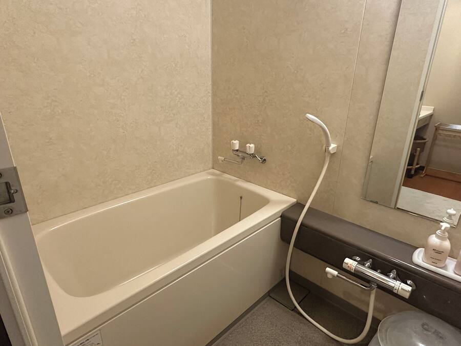 A bathroom with a bathtub, a sink, and a mirror.