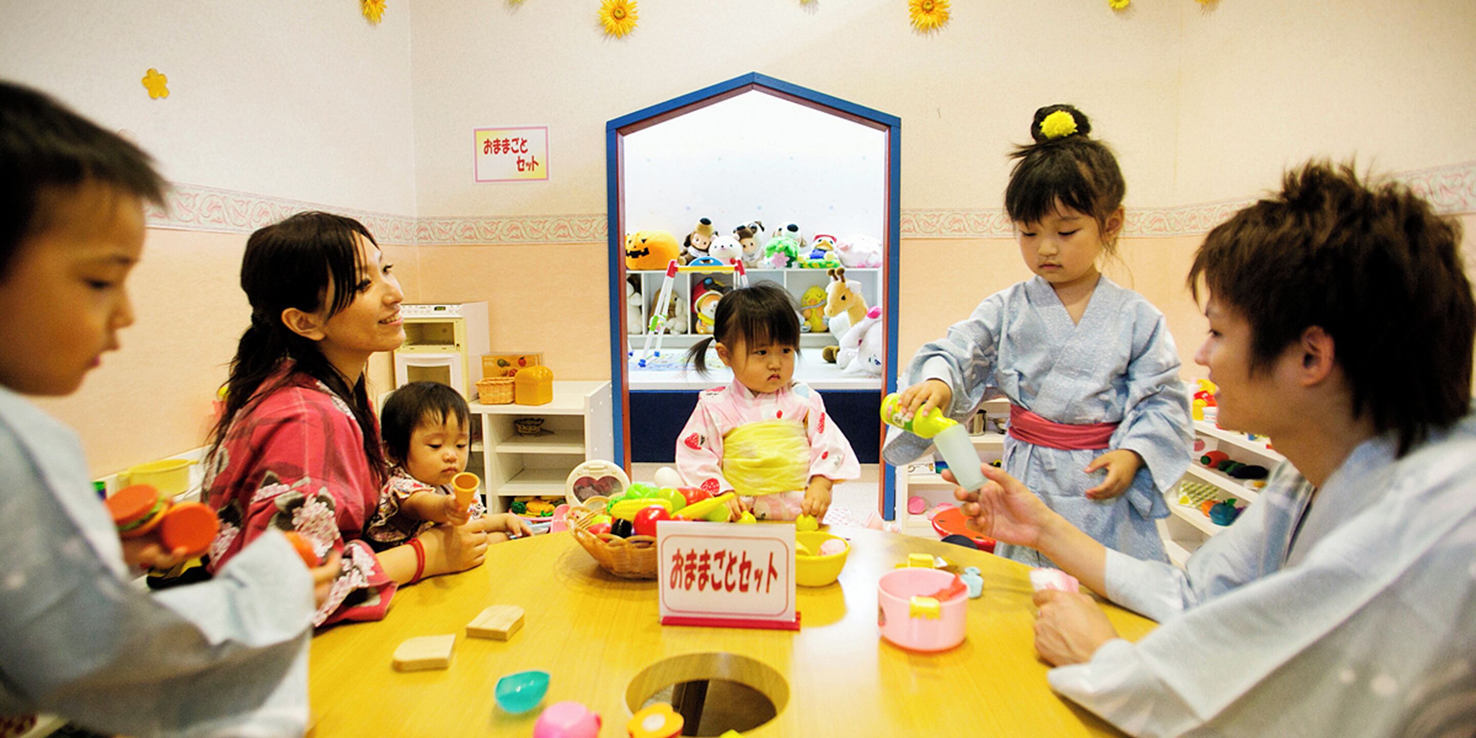 A group of children and adults engaged in a craft activity at a table with various supplies.