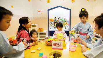 A group of children and adults engaged in a craft activity at a table with various supplies.