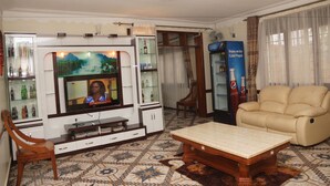 Una sala de estar con una televisión, un sofá, una mesita de centro y un refrigerador Pepsi.