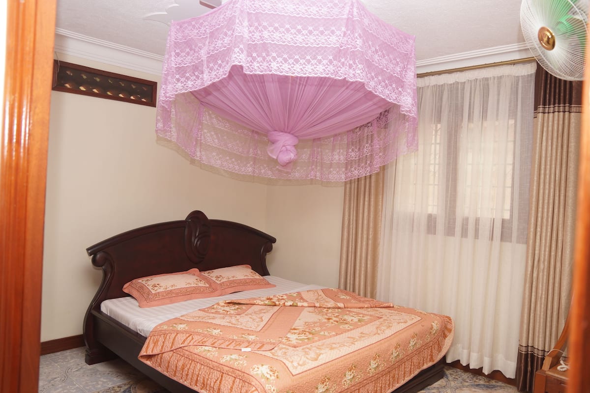 A bedroom with a bed, a ceiling fan, and curtains.