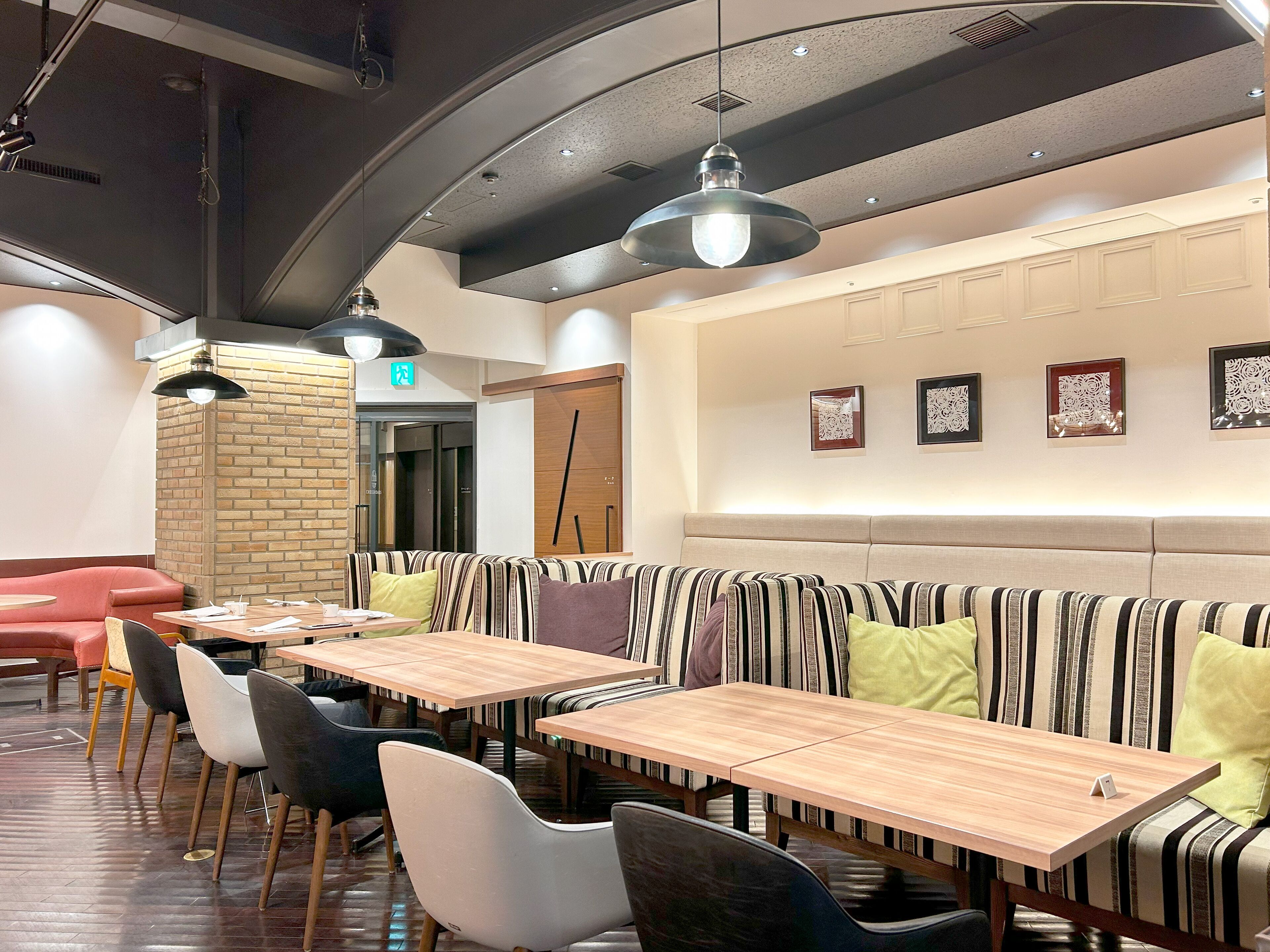 Un restaurant moderne avec des banquettes à rayures, des tables en bois et des luminaires suspendus.