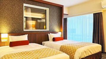 A hotel room with two beds, a large mirror, and a view of the city through the window.