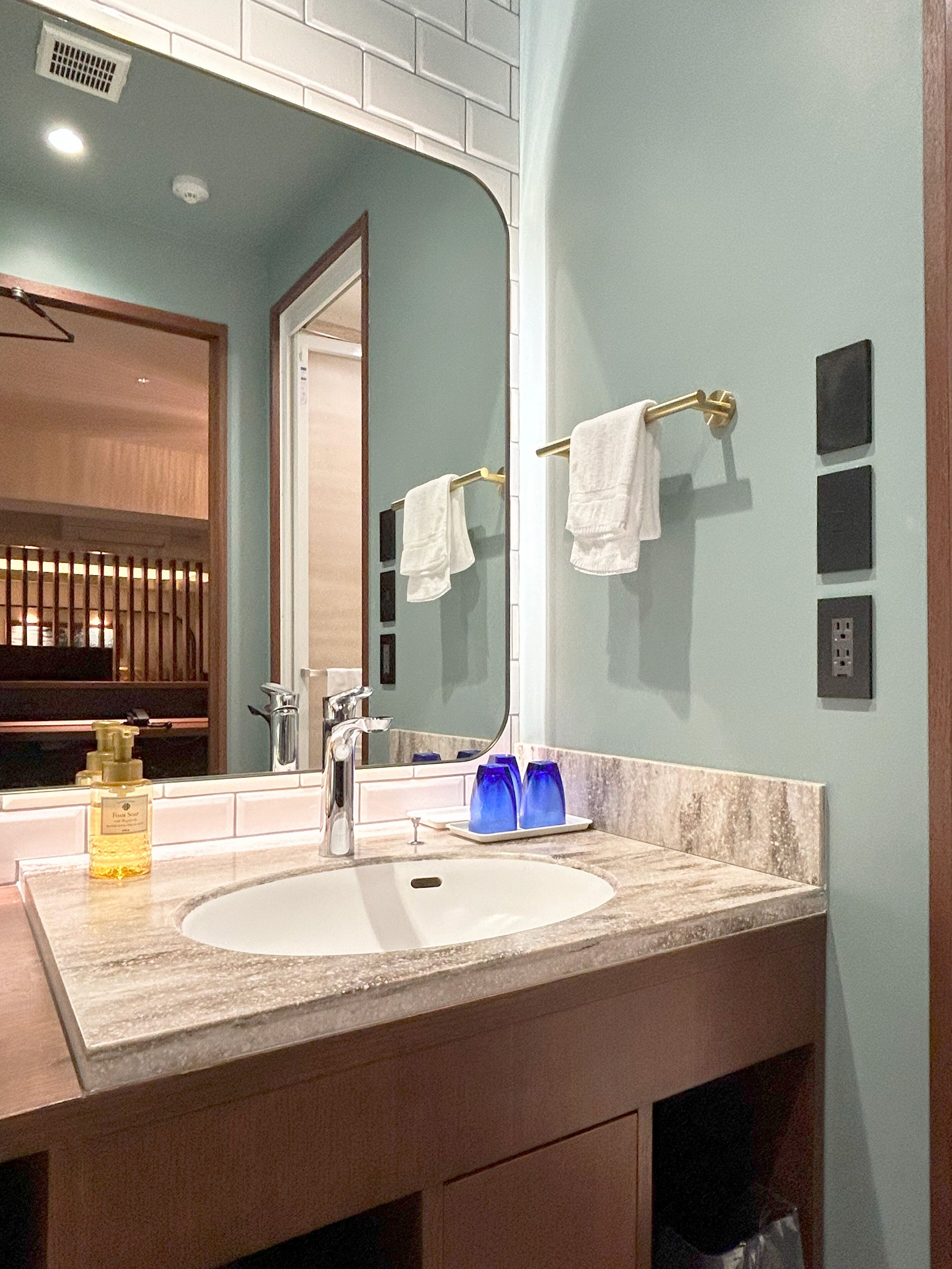 A bathroom with a sink, mirror, and towel rack.