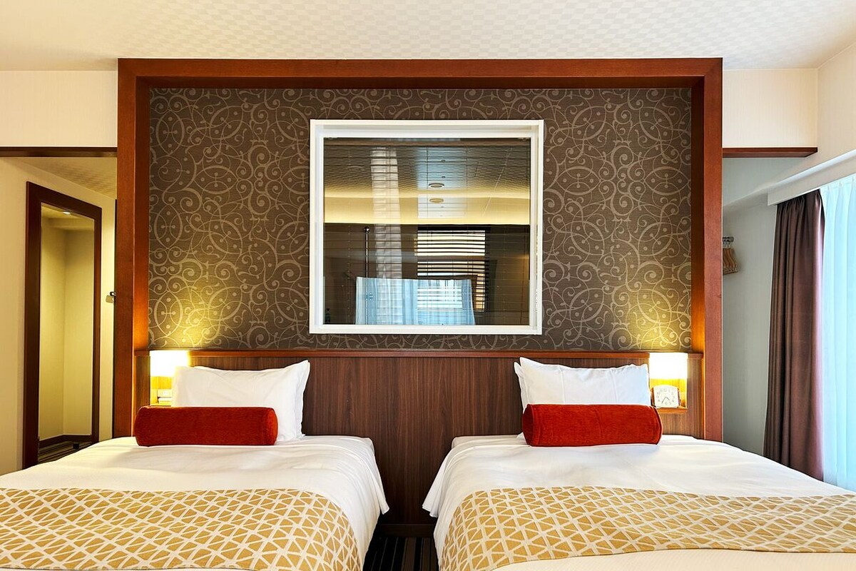 Ein Hotelzimmer mit zwei Betten, einem großen Spiegel und einer Wand mit Muster.