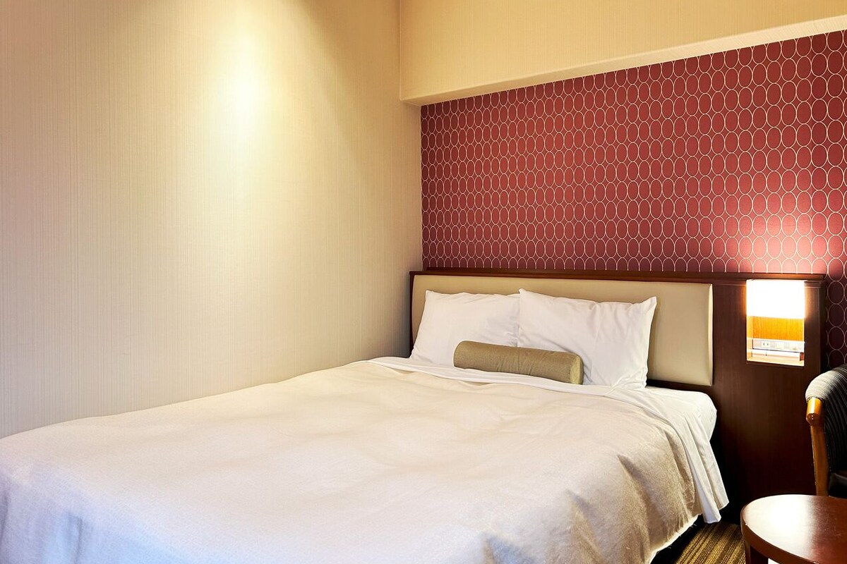 Ein Hotelzimmer mit einem Bett, einem Nachttisch und einer Wand mit geometrischem Muster.
