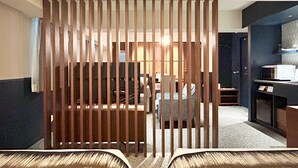 A hotel room with a wooden partition, a dining area with a table and chairs, and a kitchenette with a microwave. - Nakajimaya Grand Hotel (Shizuoka)