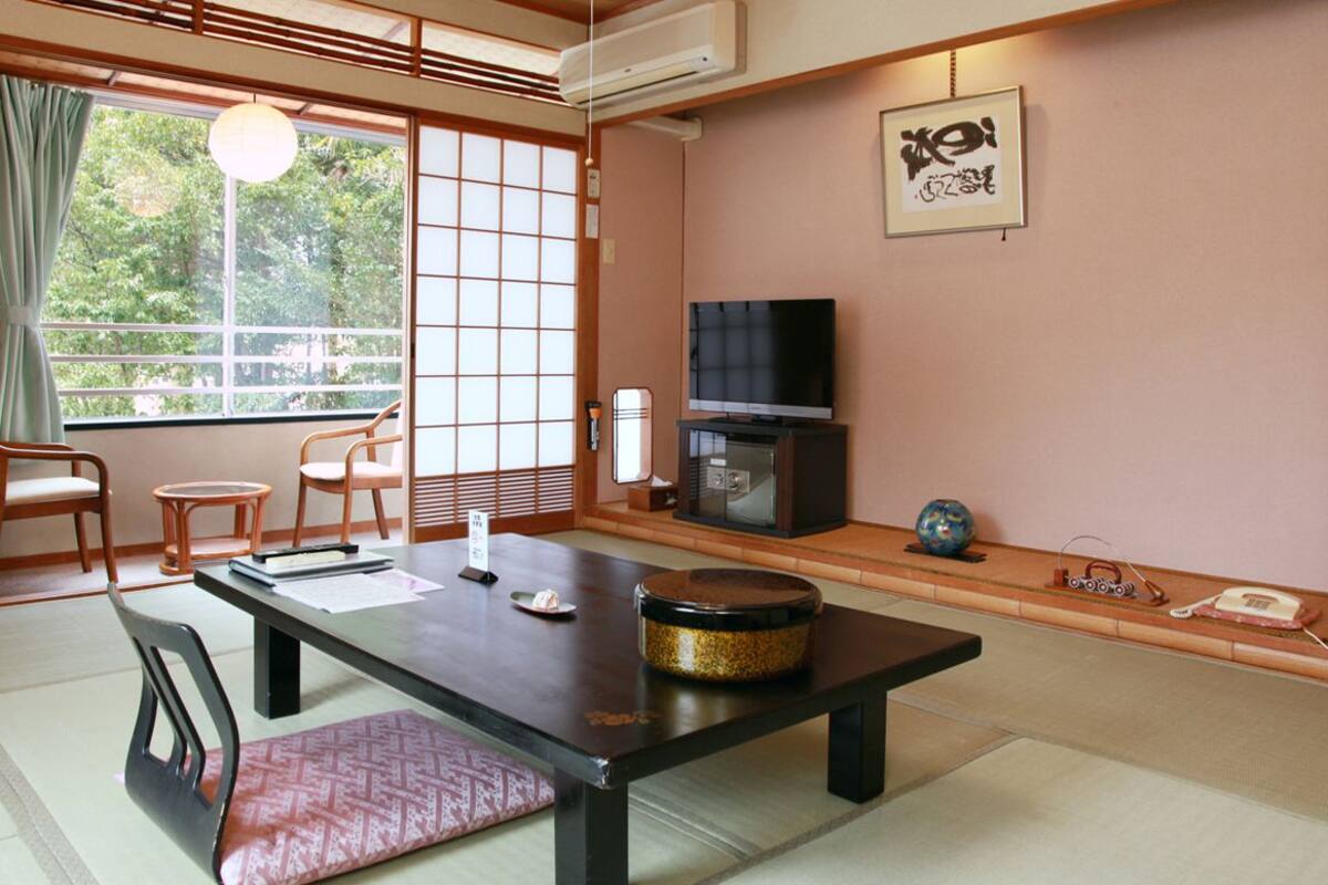 Um quarto em estilo japonês tradicional, com tatame, uma mesa baixa e uma televisão.