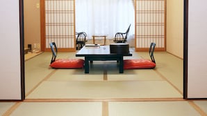 A traditional Japanese room with tatami flooring, a low table with cushions, and sliding doors. - Gyokusenkaku (Nagato)