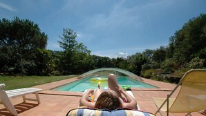 A person relaxing by a pool with lounge chairs and a clear view of the pool. - Jouandassou (Fontrailles)