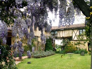 A traditional building with a tiled roof and a garden with purple flowers. - Jouandassou (Fontrailles)