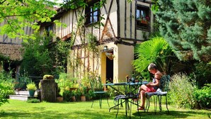 A traditional half-timbered house with a garden patio, a table, and chairs. - Jouandassou (Fontrailles)