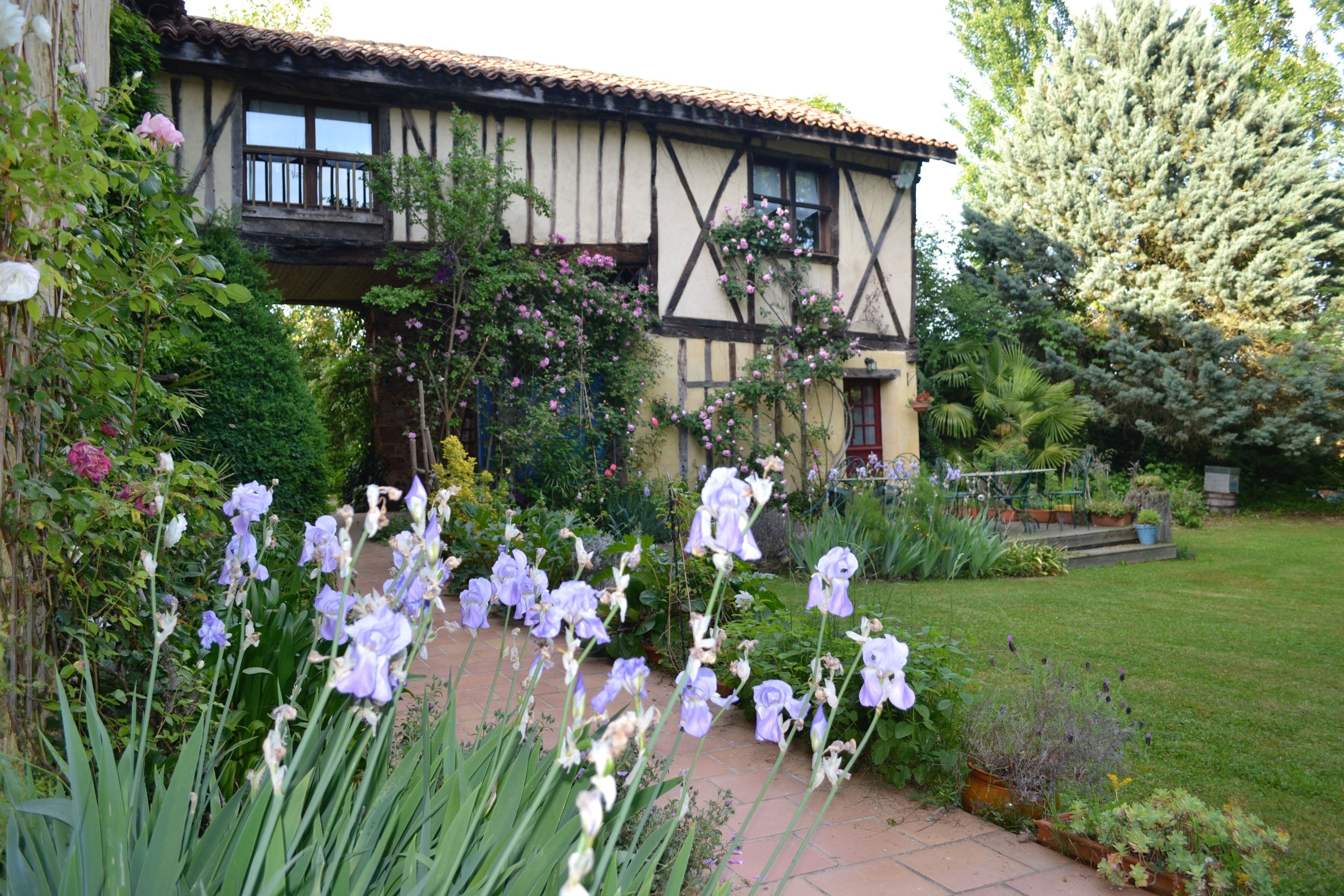 A traditional half-timbered house with a garden pathway leading to a red door.
