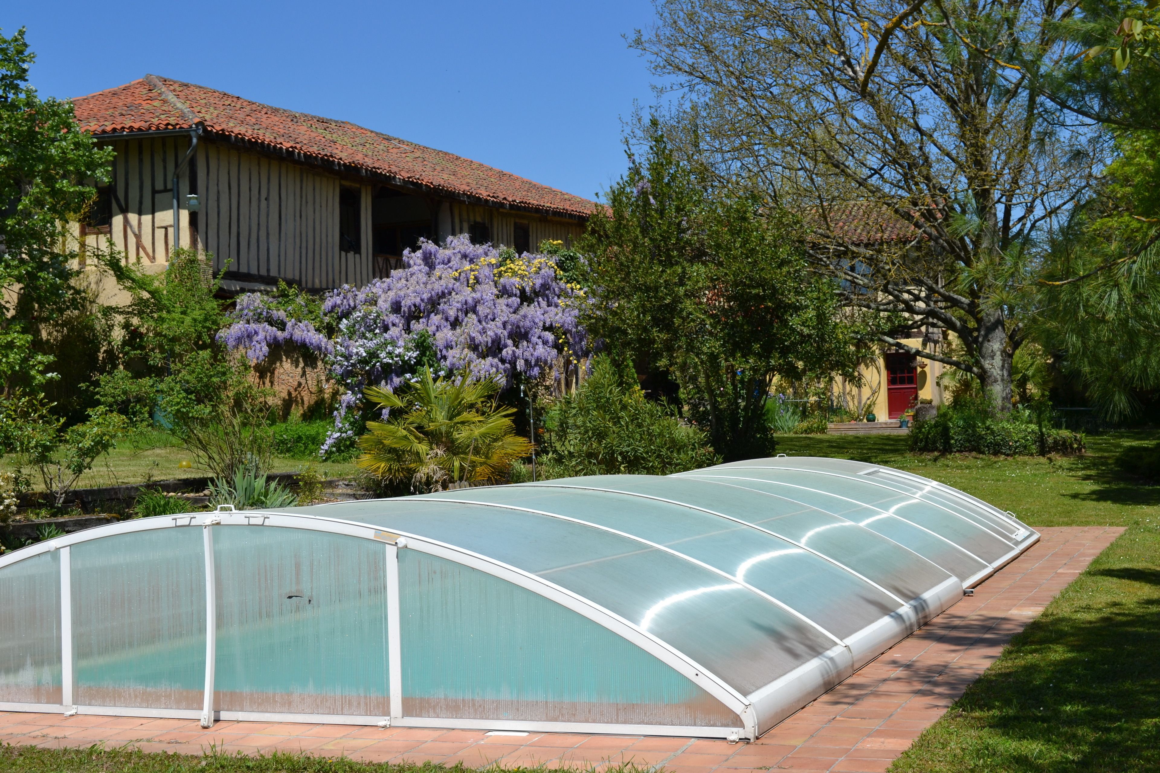 A greenhouse structure in a garden with a house in the background.