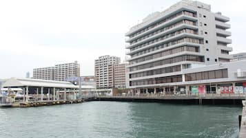 A waterfront building with multiple floors, a covered walkway, and a dock with boats.