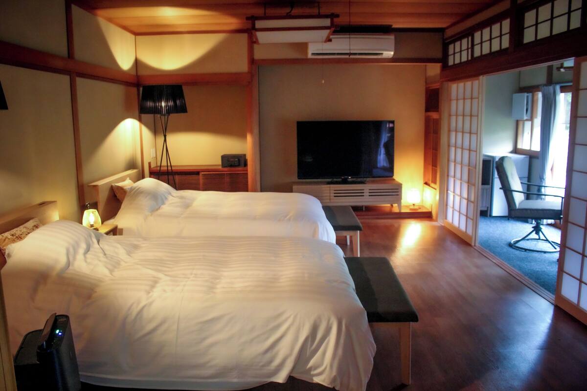 A hotel room with two beds, a television, a desk, and a chair.
