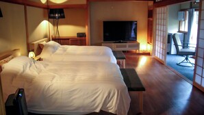 Ein Hotelzimmer mit zwei Betten, einem Fernseher, einem Schreibtisch und einem Sessel.