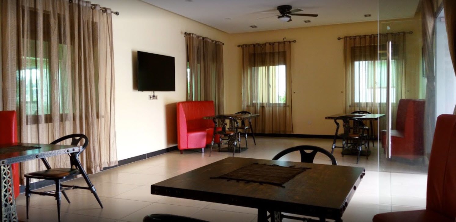 A spacious living area with a large table, several chairs, a television, and a ceiling fan.