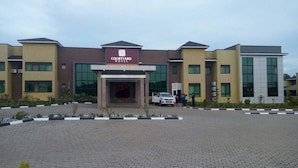 A Courtyard Hotel with a modern design, featuring a central entrance, multiple floors, and a paved driveway. - Courtyard International Hotel (Lyantonde)