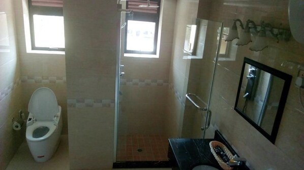 A bathroom with a toilet, a shower, and a sink. - Courtyard International Hotel (Lyantonde)