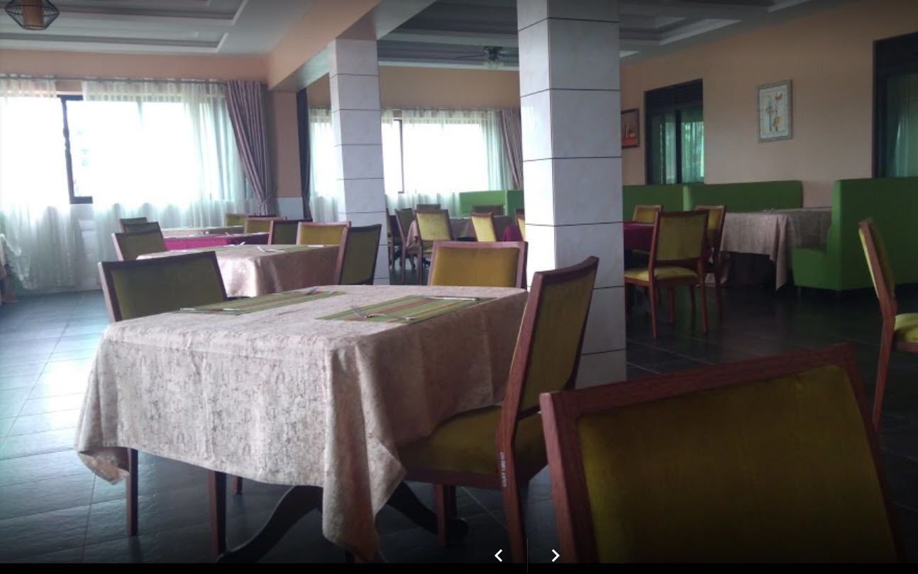 A dining area with tables and chairs, large windows with curtains, and a green partition wall.