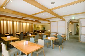 A restaurant interior with wooden tables and chairs, a high ceiling with exposed beams, and a stone archway. - Sunroute Tokuyama (Shunan)