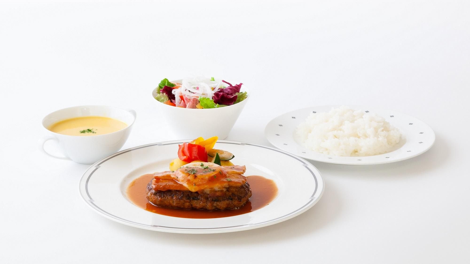 Une assiette contenant un plat de viande, un bol de soupe et une assiette de riz.
