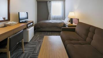 Une chambre d’hôtel comprenant un lit, un canapé, un bureau avec une télévision, une lampe et un petit réfrigérateur.
