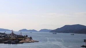 A coastal marina with boats, a crane, and a mountainous backdrop. - Sunroute Tokuyama (Shunan)
