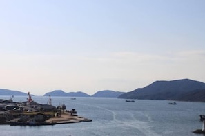 A coastal marina with boats, a crane, and a mountainous backdrop. - Sunroute Tokuyama (Shunan)
