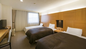 A hotel room with two beds, a desk, a television, and a window with curtains.