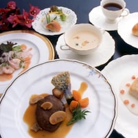 Una mesa dispuesta con diferentes platos, incluyendo un bistec con champiñones, un bol de sopa y un plato de camarones.