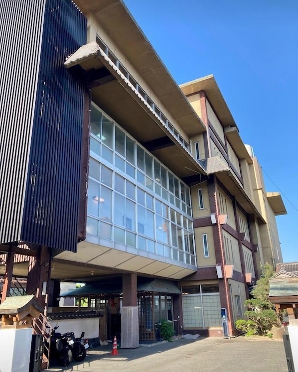 A multi-story building with large windows, a covered entrance, and a parking area with motorcycles.