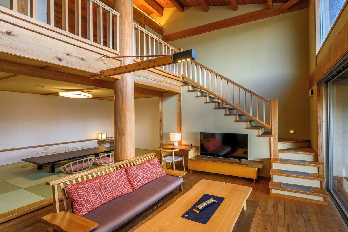 Een houten interieur met een trap, een bank, een televisie en tatami matten.
